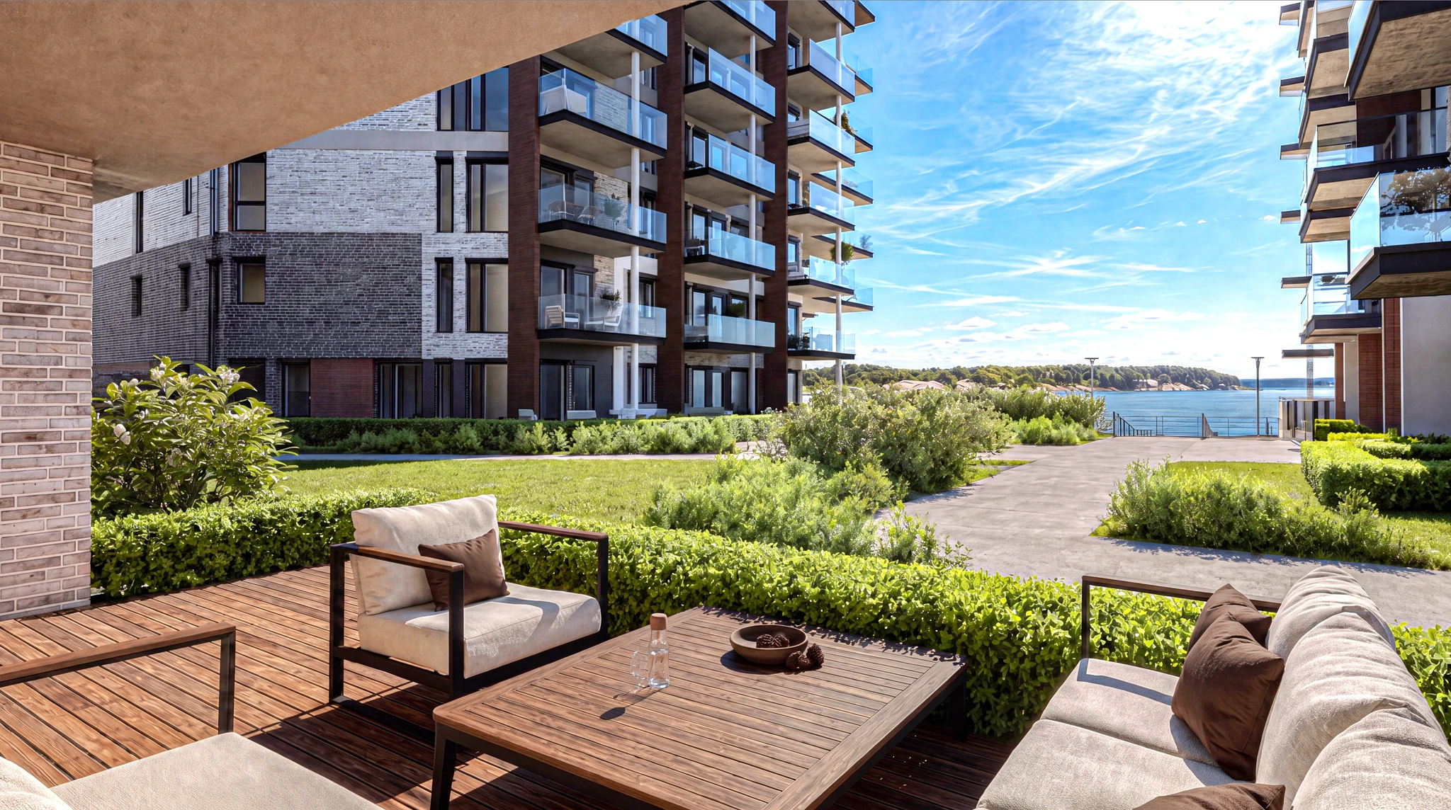 Møblert terrasse på Amalienborg Brygge med grønt gårdsrom og sjøen i bakgrunnen